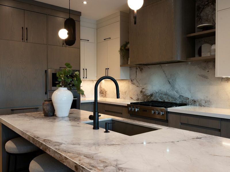 Kitchen island in veined white marble with a dark tap
